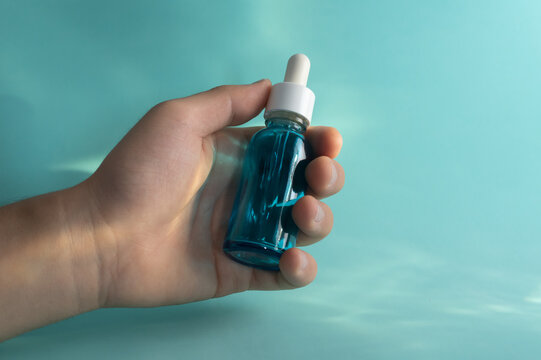 Mano sosteniendo una botella azul de &aacute;cido hialur&oacute;nico