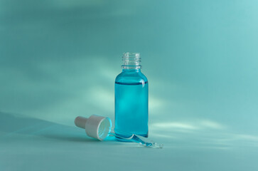 Botella azul de vidrio con gotero en un fondo azul acuático