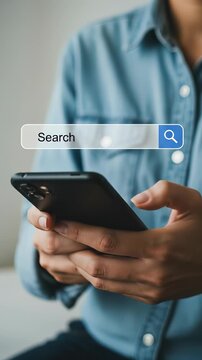 Mobile Search: Focused millennial man in a blue shirt using search engine on a smartphone for quick internet look up.