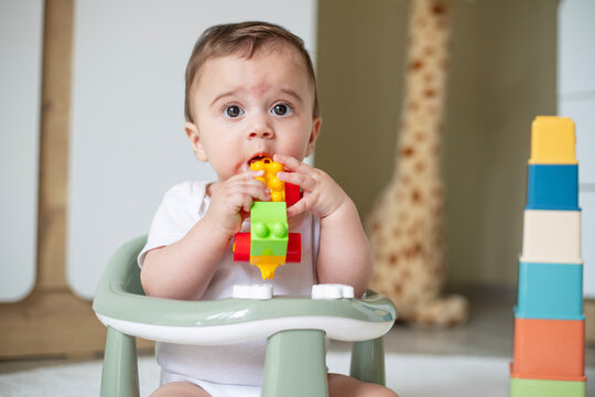 Baby, portrait and playing with toy on floor in home for sensory development, teething progress and biting. 