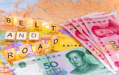 A Belt And Road Initiative concept with letter tiles and Chinese Yuan bank notes on a map of China.