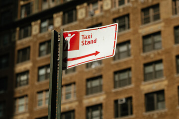 Naklejka premium Urban taxi stand sign prominently displays pictogram of person and directional arrow. Bright daylight enhances informative and functional mood of city street setting.
