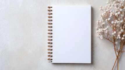 White spiral-bound notebook on textured surface, minimalist design, clean and simple aesthetic, ample negative space for text and graphics, ideal for showcasing ideas or branding.