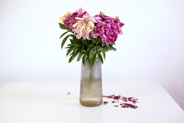 Vase filled with wilted flowers symbolizes neglect and mourning, abandonment, sadness, oblivion. Fallen leaves.