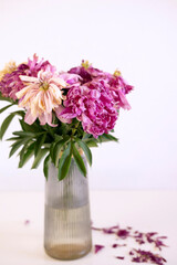 Vase filled with wilted flowers symbolizes neglect and mourning, abandonment, sadness, oblivion. Fallen leaves. vertical.