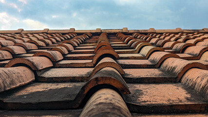 Clay tiles. Close-up photo of a clay tile roof against a blue sky background. Old and dirty clay...