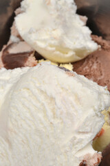 Scoops of various ice cream flavors, including vanilla and chocolate, are piled in a metal bowl