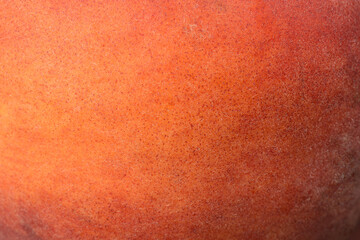 A close-up shot captures the fuzzy, reddish-orange skin of a ripe peach, revealing its natural...