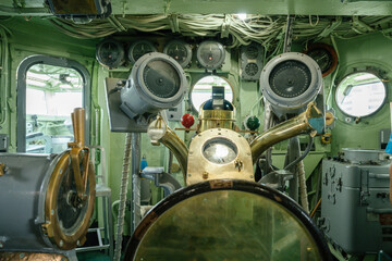 Interior of a historical ship bridge filled with analog navigation instruments and a brass compass. The room features vintage equipment used for maritime steering and direction control. © DenisProduction.com