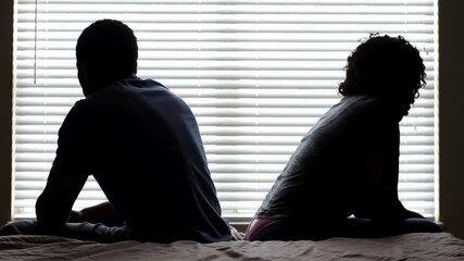 A couple quarreling concept of family relationship problems divorce, black silhouette of man and woman sitting at bed back to back resentment towards each other window in dark room - Powered by Adobe