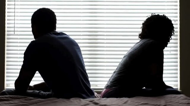 A couple quarreling concept of family relationship problems divorce, black silhouette of man and woman sitting at bed back to back resentment towards each other window in dark room