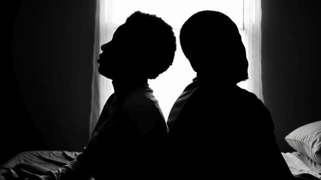 A couple quarreling concept of family relationship problems divorce, black silhouette of man and woman sitting at bed back to back resentment towards each other window in dark room