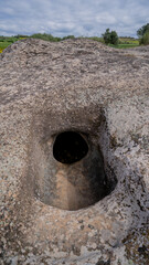 Prehistoric Domus de Janas tomb carved in stone, surrounded by lush Sardinian forest