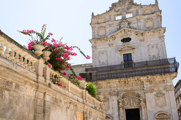  Historic building with ornate architecture and vibrant flowers in pots against a clear blue sky