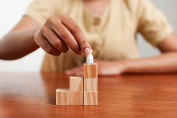 Building success child assembling wooden blocks home educational activity indoor close-up growth mindset