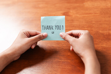Gratitude gesture thank you note indoor setting personal interaction warm environment close-up view