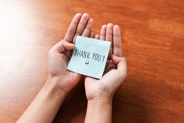Grateful gesture hands holding thank you note indoor setting personal connection warm atmosphere