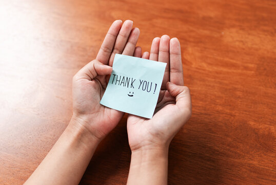Grateful gesture hands holding thank you note indoor setting personal connection warm atmosphere