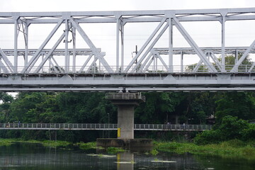 Fototapeta premium Steel Truss Railway Bridge Over River – Infrastructure in Green Landscape