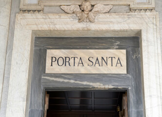 Naklejka premium Porta Santa entrance with intricate marble details and angel sculpture above the doorway in a historic building