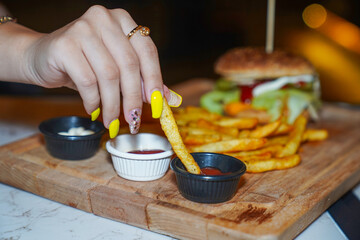 Girl  dips fries in sauce at restaurant