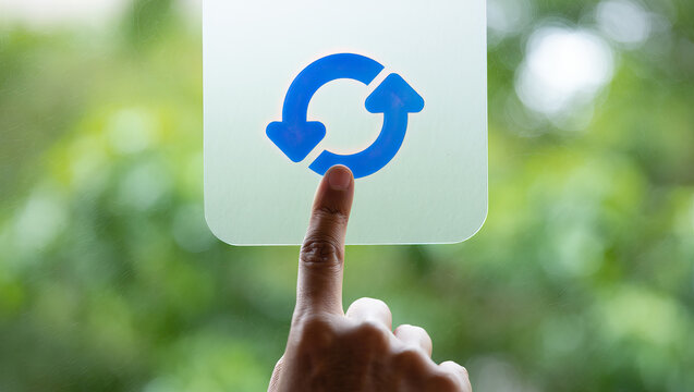 Refreshing Perspectives A Finger Tapping a Refresh Button on a Transparent Screen with a Green Foliage Background Symbolizing Renewal and Restarting Processes