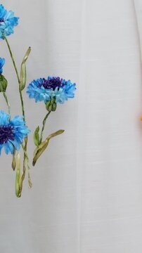 Beautiful embroidery flowers on cotton fabric. Product of needlework on a piece of embroidery. Needlework is decorative sewing and textile arts handicrafts. How to stitch embroider flowers on clothes.