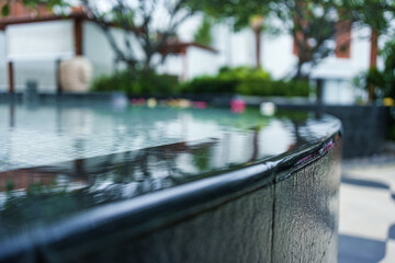 Infinity edge pool surface with clear water flowing over black tile in luxury resort