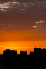 Orange sky. Morning in town. Panorama of the metropolis. Silhouette of houses. Peaceful life. Calm sky. Color gradient in nature. Heavenly landscape. Urban skyline.