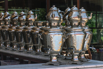 Shiny metal samovars and teapots for brewing tea on top. The interior of a cafe in Turkey with a view of tea brewing appliances. Tea ceremony and national tea-making traditions.