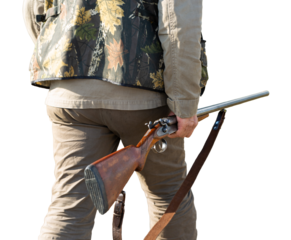Mature man hunter with gun while walking on field.