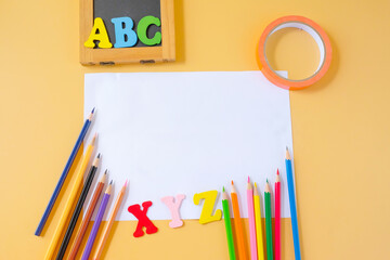 Colored pencils and blank paper sheet on color background .