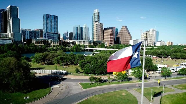 The texas flag waves proudly over the austin skyline on a sunny day