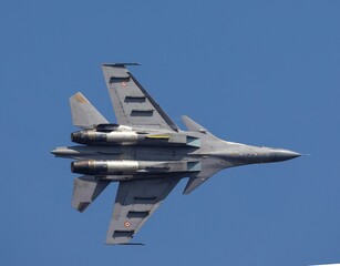 A powerful modern fighter jet is captured mid-flight against a pristine, clear blue sky. The...