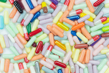 Macro texture of a large heap of colorful pharmaceutical capsules. A conceptual pattern representing the medicine industry, drug manufacturing, and healthcare themes like addiction.