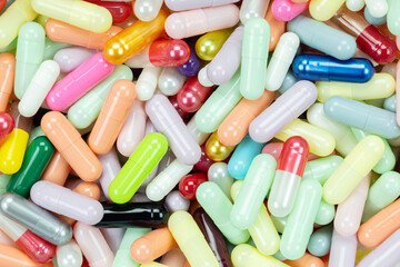 Pastel colored capsule pile creating a soft pattern. A gentle healthcare and wellness background texture, representing vitamins, supplements, and light medicine for family health.