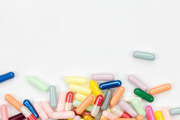 Minimalist medical background with a corner pile of colorful capsule pills. A healthcare or pharmacy concept template for treatment and medicine topics with extensive copy space.