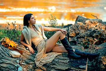Autumn woman in golden sunlight. Autumn portrait of stylish girl with leaves. Autumn woman face in autumn park. Female model by falling foliage. Young woman walking through yellow leaves.