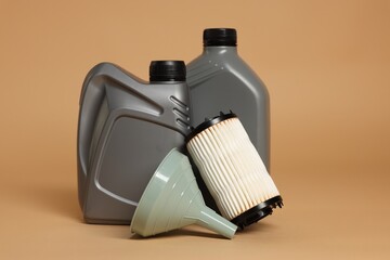 Motor oil in plastic canisters, filter and funnel on beige background