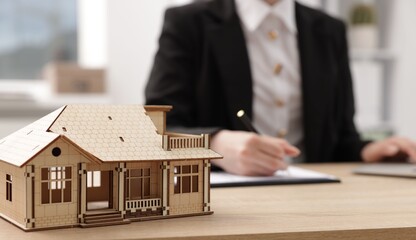 Real estate agent working at desk in office, focus on house model