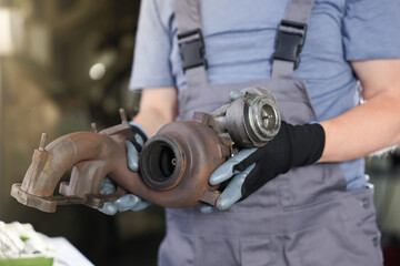 Auto part. Professional mechanic with turbocharger indoors, closeup