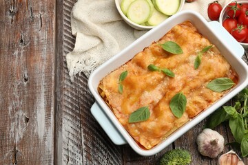 Tasty vegetarian lasagna in baking dish and ingredients on wooden table, flat lay. Space for text