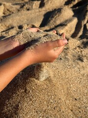 Child's Hands Holding Sand on Sunny Beach