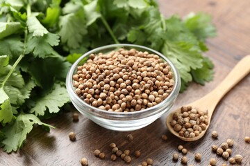 Fresh cilantro and coriander seeds on wooden table, closeup
