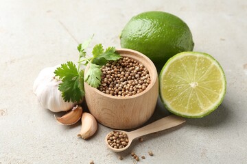 Coriander seeds, fresh cilantro, lime and garlic on light textured table, closeup