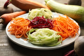 Different noodles and vegetables on wooden table, closeup