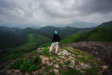 Confident woman standing on a rocky cliff during a trek in Windy Walk Forest, Vagamon, Idukki, Kerala.