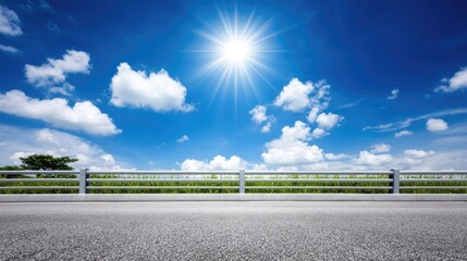 Paved highway under a bright blue sky with fluffy clouds and green meadows in a summer landscape