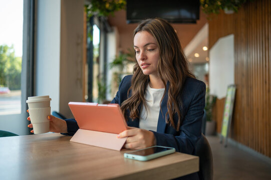 Businesswoman working on tablet and drinking coffee in cafe