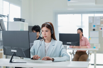 Happy businesswoman with headphones working on PC in call center office, young female technical...